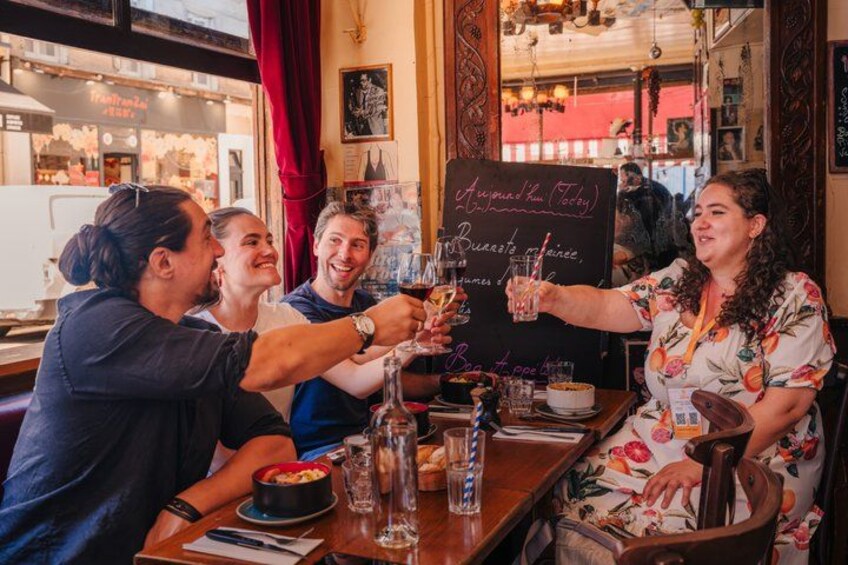 Un groupe de personnes trinquant avec des boissons dans un restaurant où le menu est écrit sur un tableau noir. 4