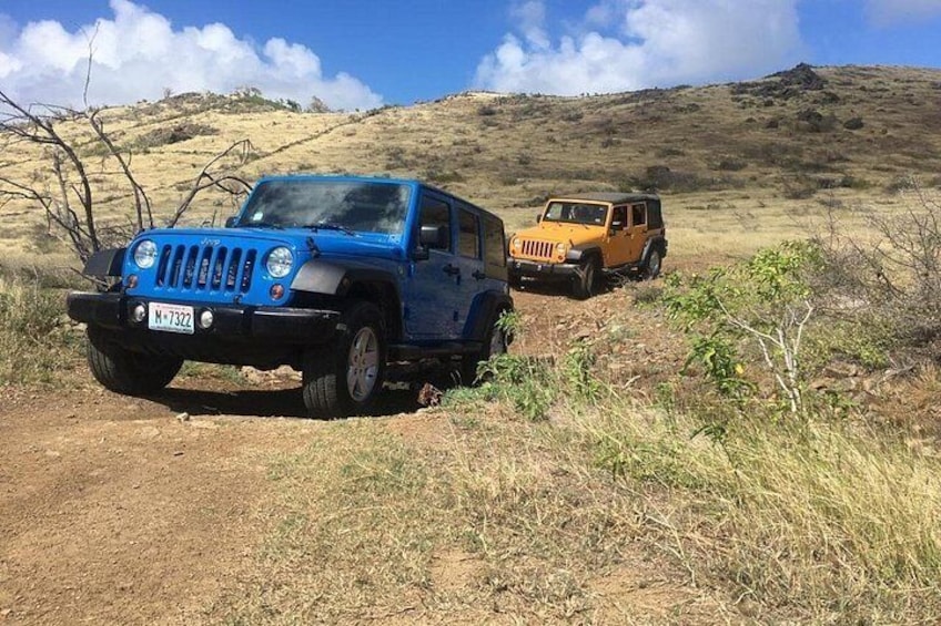 Two off-road vehicles on a dirt path in a dry, hilly landscape. 1