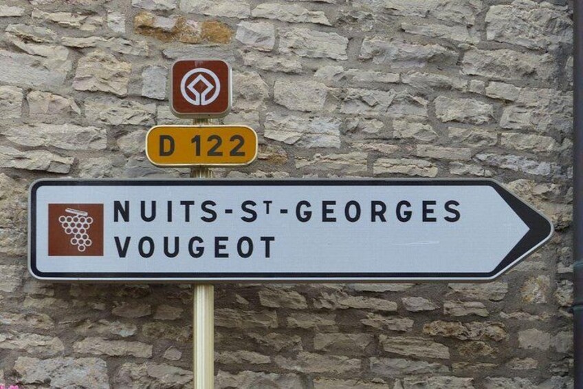A directional sign with 'NUITS-ST-GEORGES VOUGEOT' and a symbol of grapes. 2
