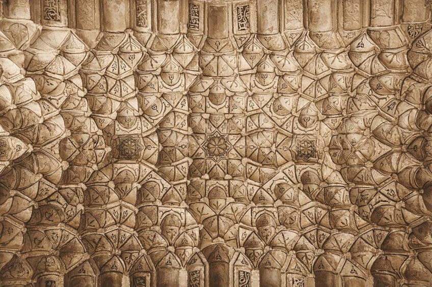 En detaljerad stenmur med intrikata geometriska mönster och arabisk kalligrafi. 5