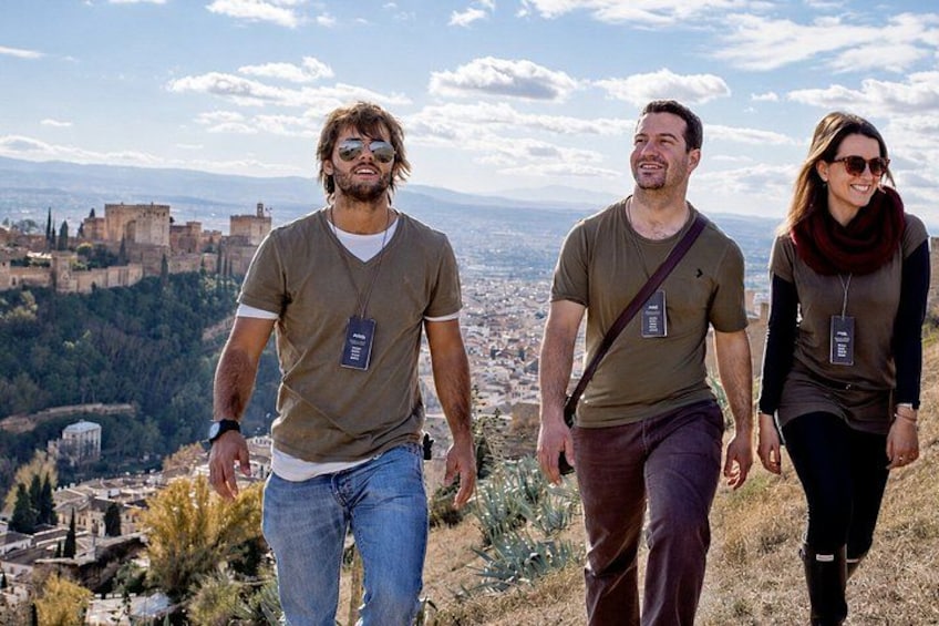 Three people walking on a hill with a historic castle in the background. 1