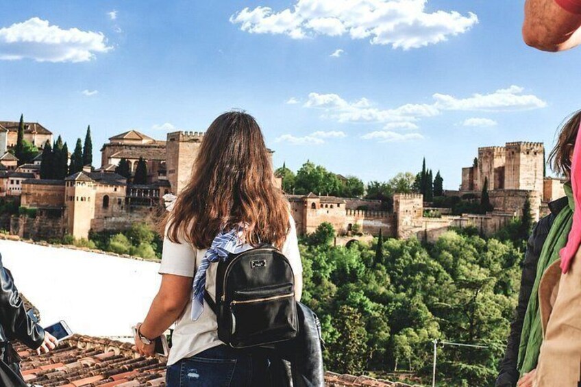 Una persona con uno zaino che guarda una città storica con edifici antichi e cielo sereno. 5