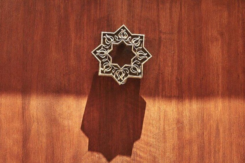 Una superficie in legno con un oggetto metallico decorativo caratterizzato da un elaborato motivo geometrico. 3