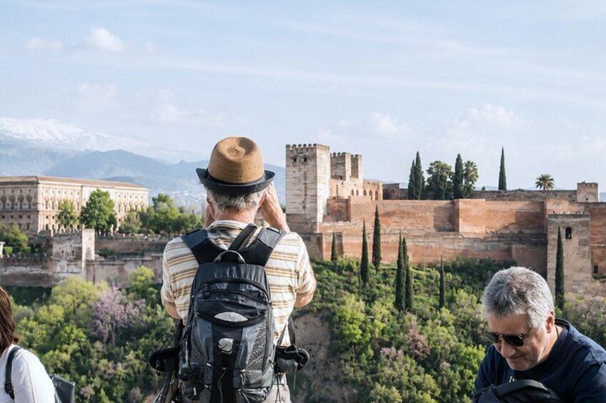 Un uomo con cappello e zaino che osserva un castello storico. 4