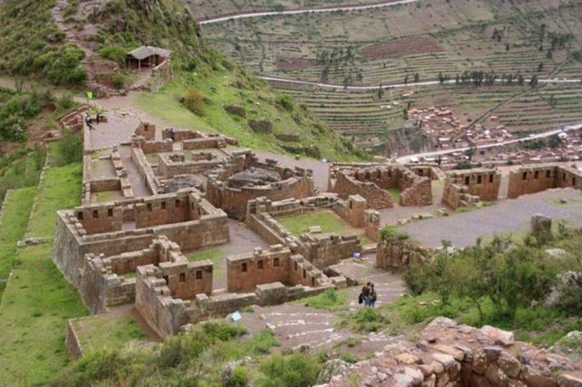 Ancient ruins with stone structures and terraced fields in the background. 3