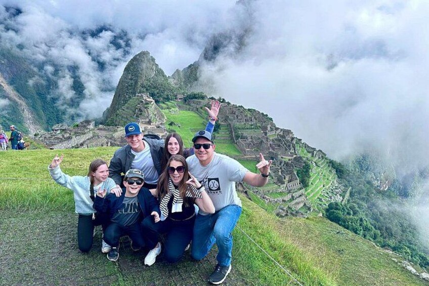 Un groupe de personnes posant devant le Machu Picchu, avec les ruines emblématiques de la montagne en arrière-plan. 1