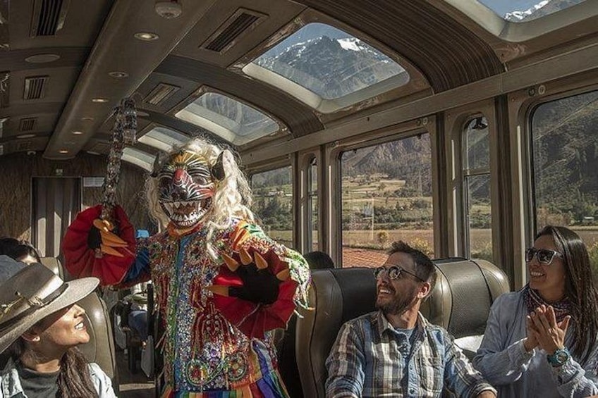 A person in a colorful costume inside a train carriage with passengers. 5