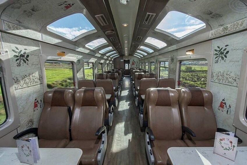 A train interior with rows of seats, overhead windows, and patterned walls. 2
