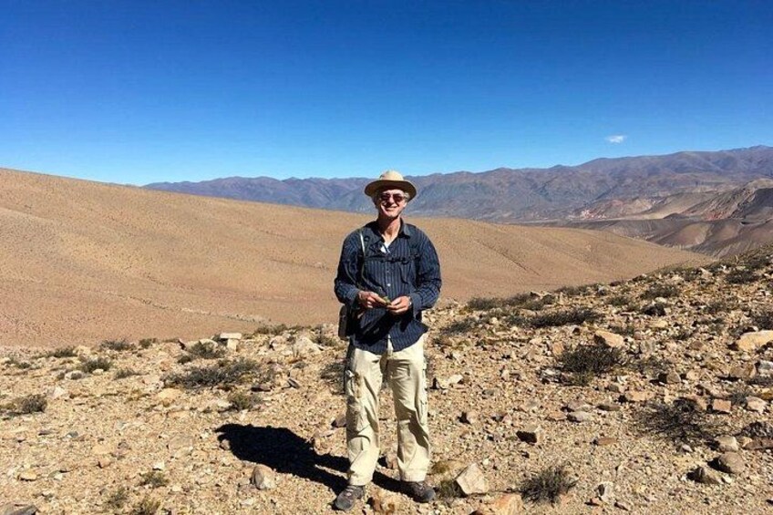 A person standing on rocky terrain with a desert landscape and mountains in the background. 2