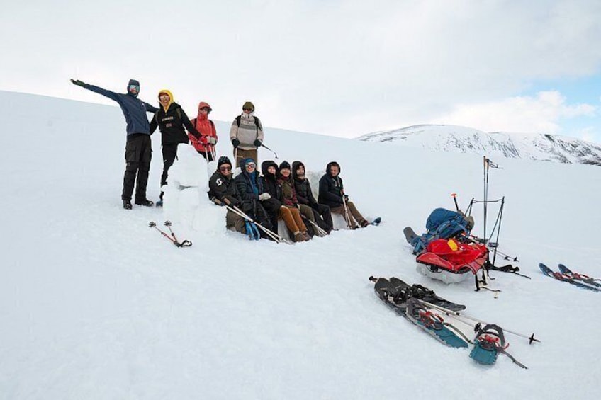 A group of people on a snowy mountain slope with skis and snowboards scattered around. 3