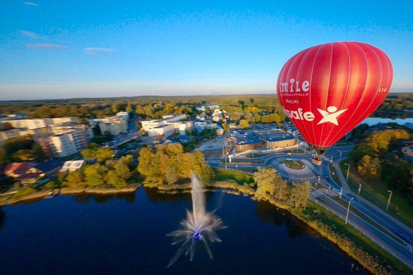 Un globo aerostático sobre una ciudad con edificios y un río. 2