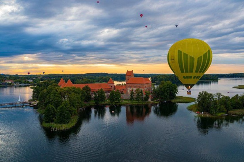 Un castillo a orillas de un lago con globos aerostáticos en el cielo. 5