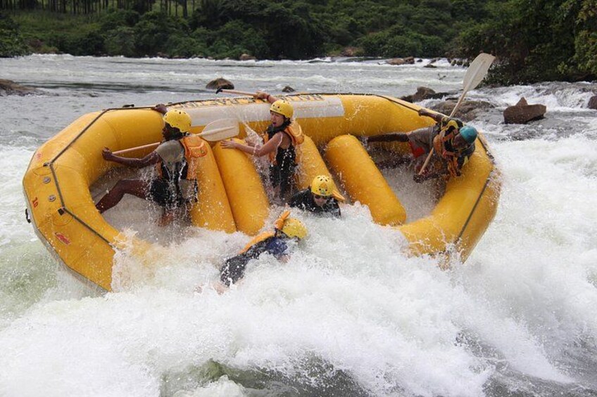 A group of people in a yellow inflatable raft navigating through whitewater rapids. 1