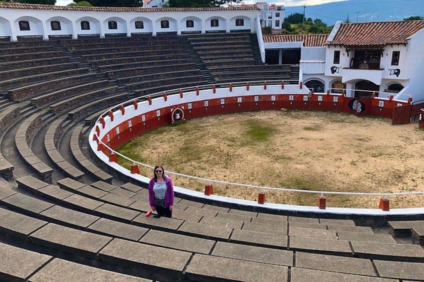 A large, empty amphitheater with tiered seating and a central open area. 3