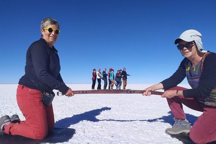Two people pulling a sled on a snowy plain with a group of people in the background. 2