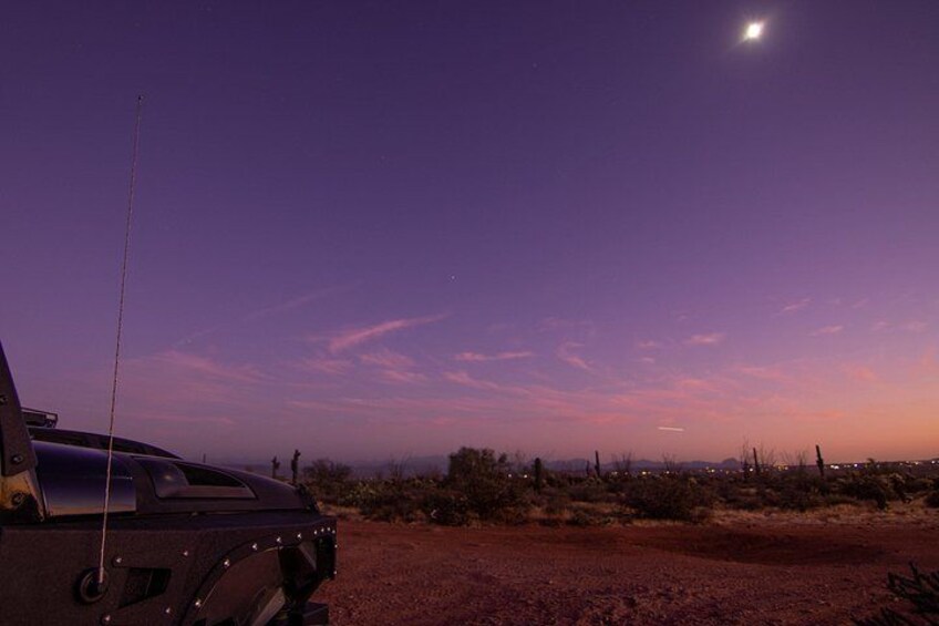Un vehículo estacionado en un paisaje desértico, con cielo despejado y una luna visible. 2