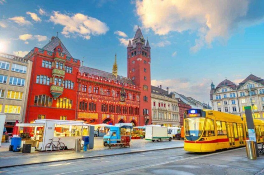 Un tranvía en una ciudad con edificios históricos y una torre destacada. 1