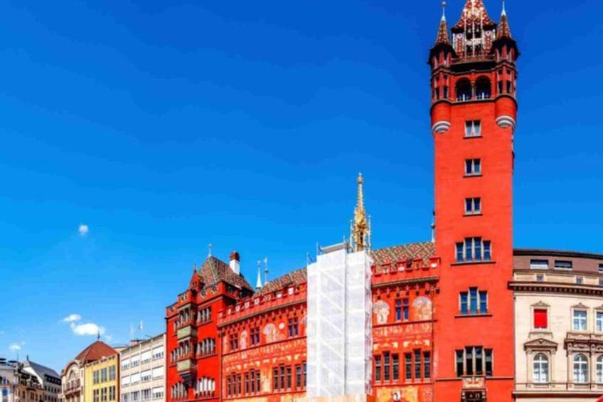 Un edificio rojo con una torre, una estructura blanca al frente y otros edificios al fondo. 5