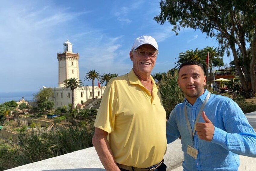 Dos personas frente a un edificio costero con un faro. 2