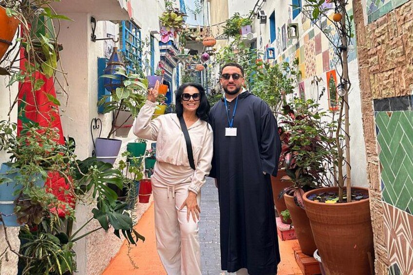 Un callejón estrecho con edificios coloridos, plantas en macetas y una persona con vestimenta tradicional. 2