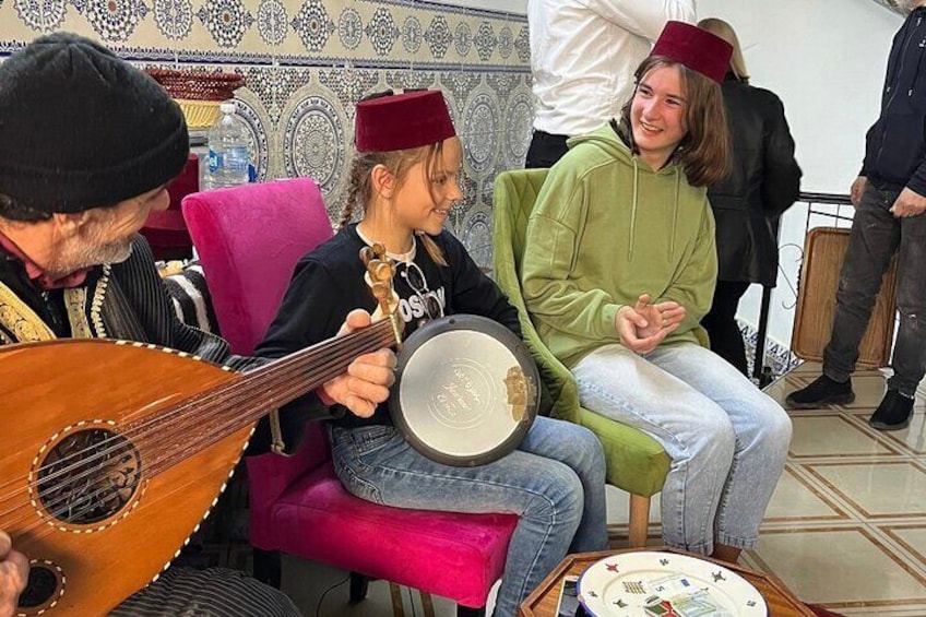 Una persona suona uno strumento a corda, un'altra tiene un tamburello e una terza indossa una felpa verde. 5
