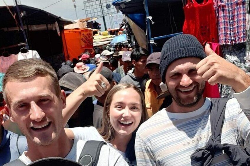 A crowded outdoor market with people and various stalls. 4