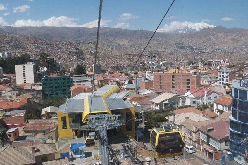 A cable car system in a city with buildings and mountains in the background. 1