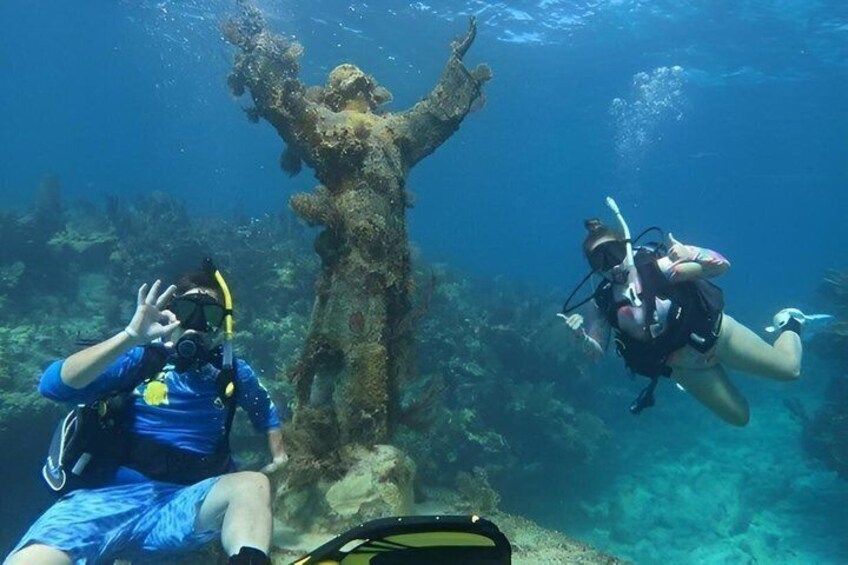 Two scuba divers underwater with a large coral formation in the background. 5
