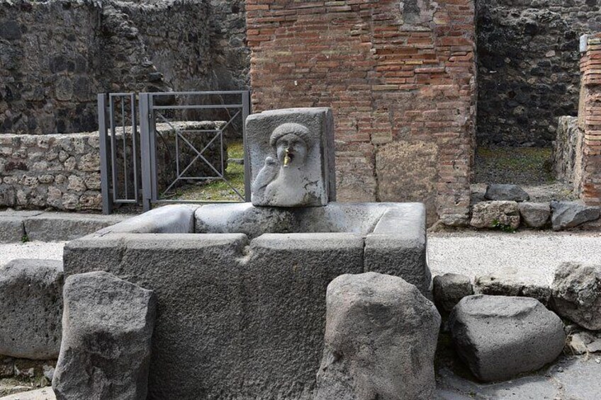 A stone structure with a relief sculpture, surrounded by stone blocks and a metal gate. 4