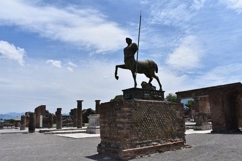 A statue of a rider on horseback, ancient ruins, and a clear sky. 3