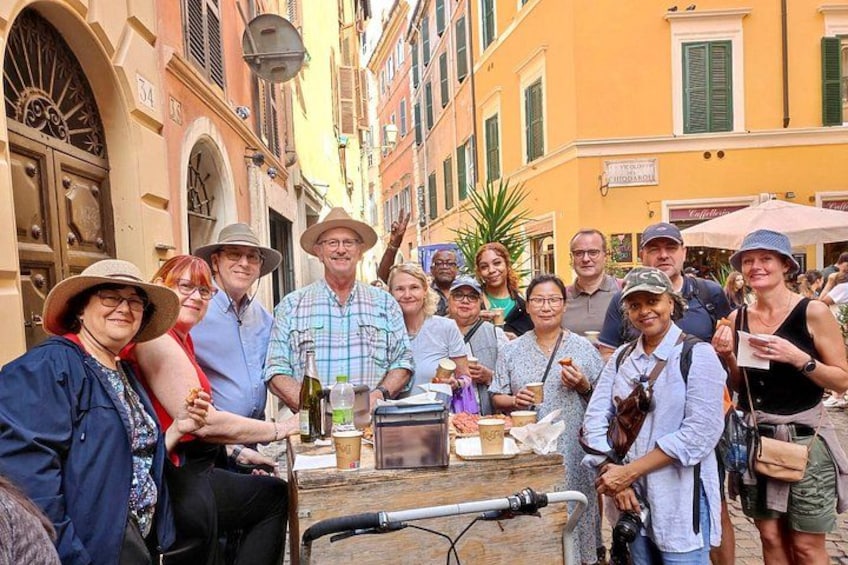 Un grupo de personas reunidas alrededor de un carrito de comida callejera en un pueblo histórico europeo. 1