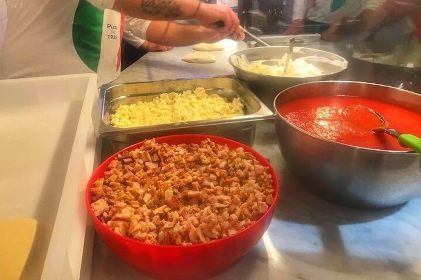 Un bufé con diferentes opciones de comida, incluyendo un tazón rojo de carne picada, una olla de salsa roja y recipientes con queso y otros ingredientes. 3