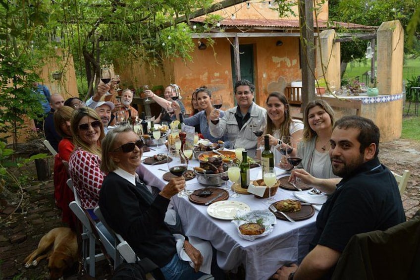 Un groupe de personnes est assis à une table à l’extérieur, où elles prennent un repas et boivent des boissons. 3