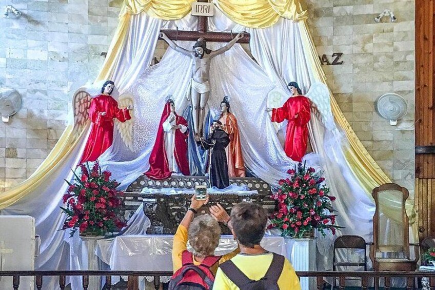 A religious altar with statues, flowers, and draped fabric. 4