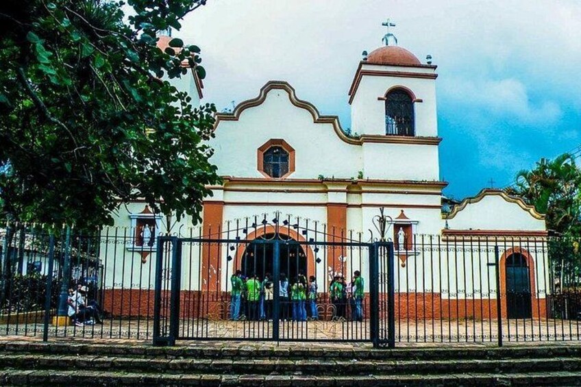 A church with a bell tower, arched entrance, and a fence in front. 3