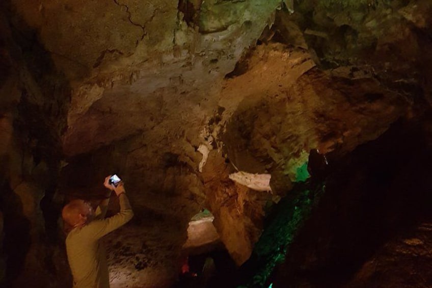 A person taking a photo inside a cave with stalactites. 5