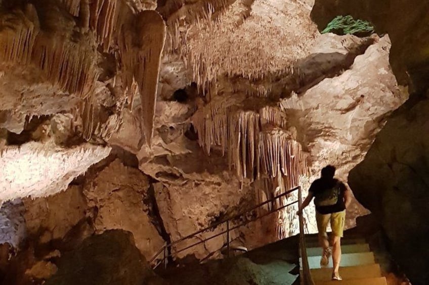 A person walking on a staircase inside a cave with stalactites. 3