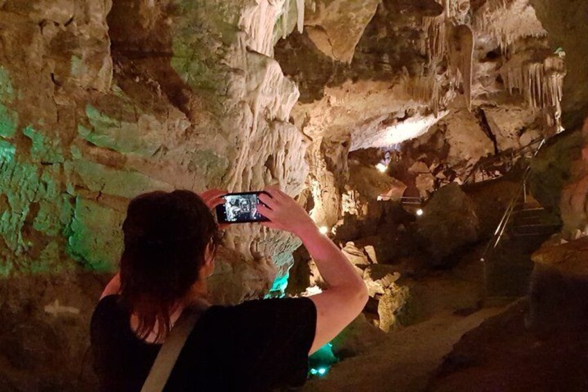 A person taking a photo inside a cave with stalactites and a staircase. 4