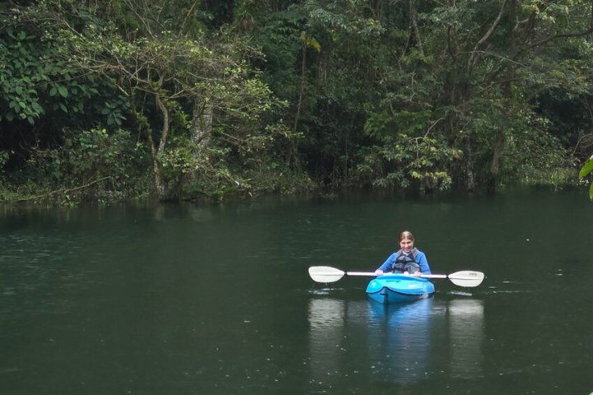 A person kayaking on a calm river surrounded by dense greenery. 1