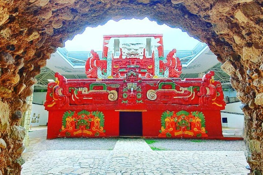 A red traditional Chinese gate with intricate carvings, set within a rocky cave-like structure. 2