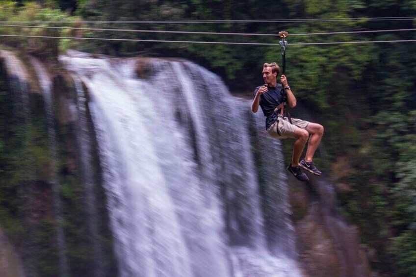 A person zip-lining over a waterfall. 1