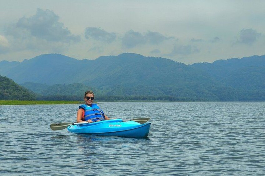 Une personne pratiquant le kayak sur un lac paisible, avec des montagnes en arrière-plan. 1