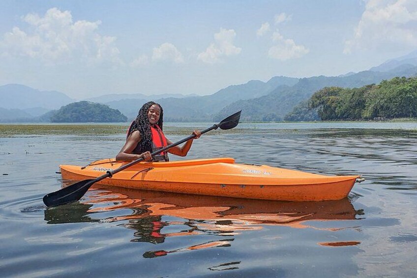 A person in a kayak on a calm body of water with mountains in the background. 4