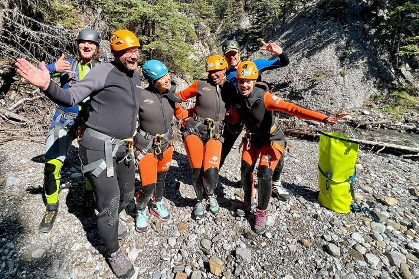 En gruppe mennesker i outdoor-tøj, tilsyneladende i gang med klatring eller rebudsvingning, med klippelandskab og træer i baggrunden. 4