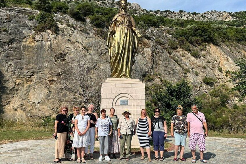 Un groupe de personnes se tient devant une statue, sur le flanc d’une colline rocheuse. 4