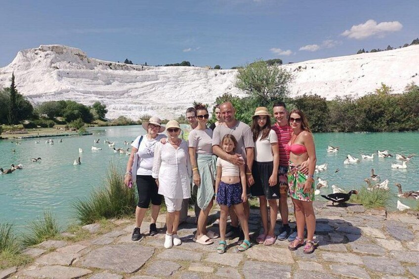 A group of people standing by a body of water with a white cliff in the background. 5