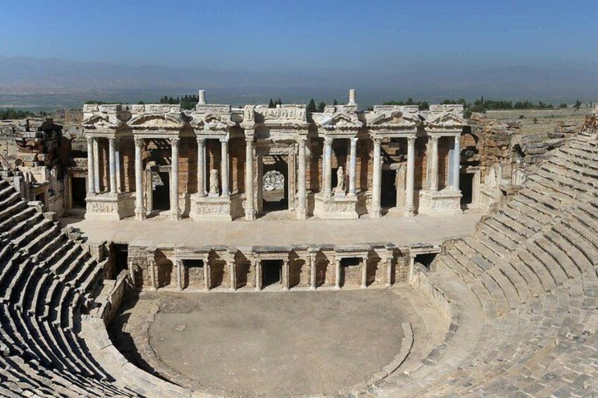 An ancient amphitheater with stone seating and a central stage. 2
