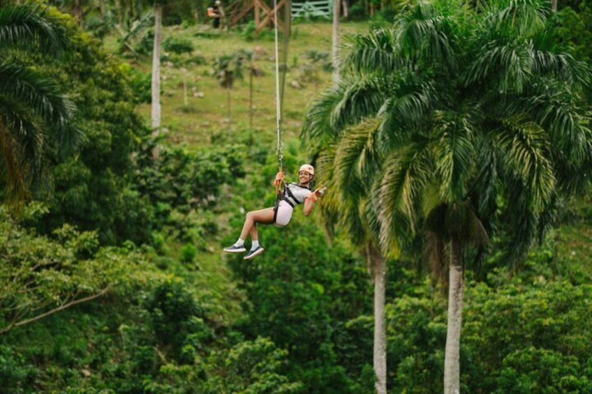 A person swinging on a rope between trees in a lush green forest. 1