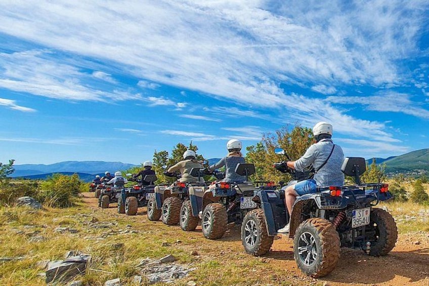 Un grupo de personas en cuatrimotos por un sendero de tierra, con montañas al fondo. 5