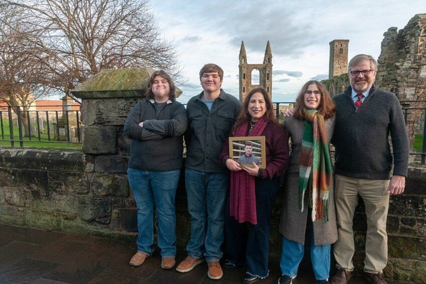 A group of people standing in front of a stone wall with a historic building in the background. 5